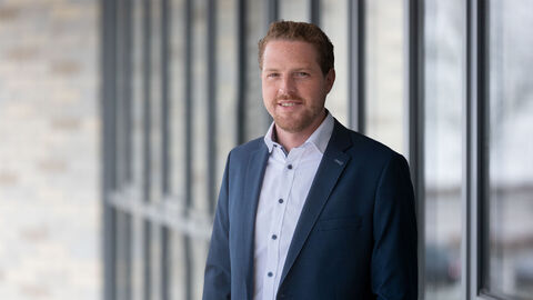 Pressesprecher Tobias Schwarz vor Glaswand 