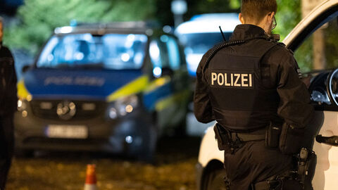 Polizist kontrolliert Fahrzeug, Hintergrund Polizeiauto