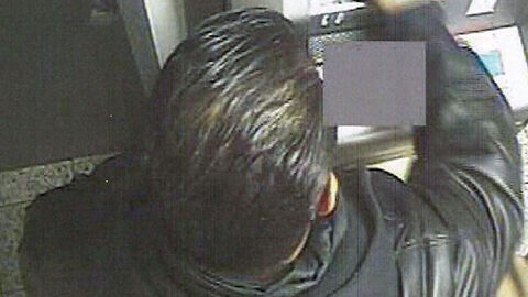 Unbekannter Täter an einem Geldautomaten in Rückansicht