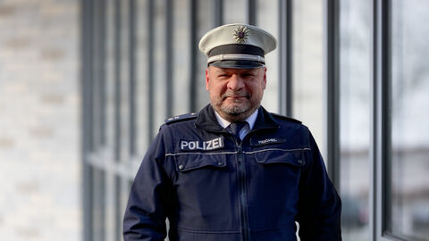 Schutzmann vor Ort Oliver Reichel uniformiert vor Glaswand 