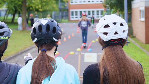 Schülerinnen und Schüler durchqueren eine Parcours mit einem E-Scooter
